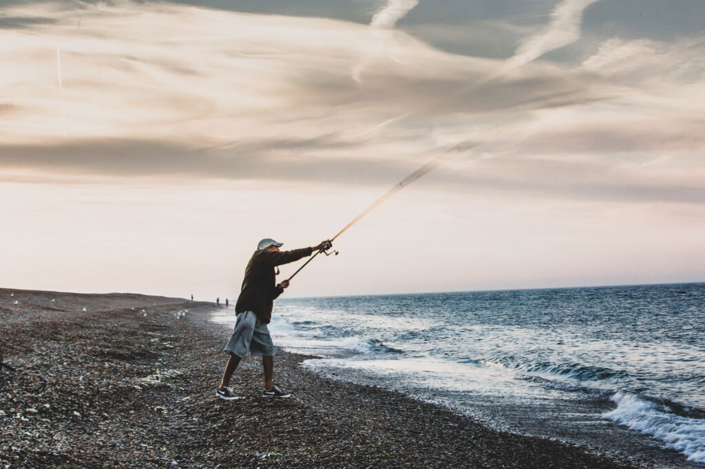 An old man sea fishing on a beach at sunset in Norfolk - Blanc Creative Stock Photography Norwich