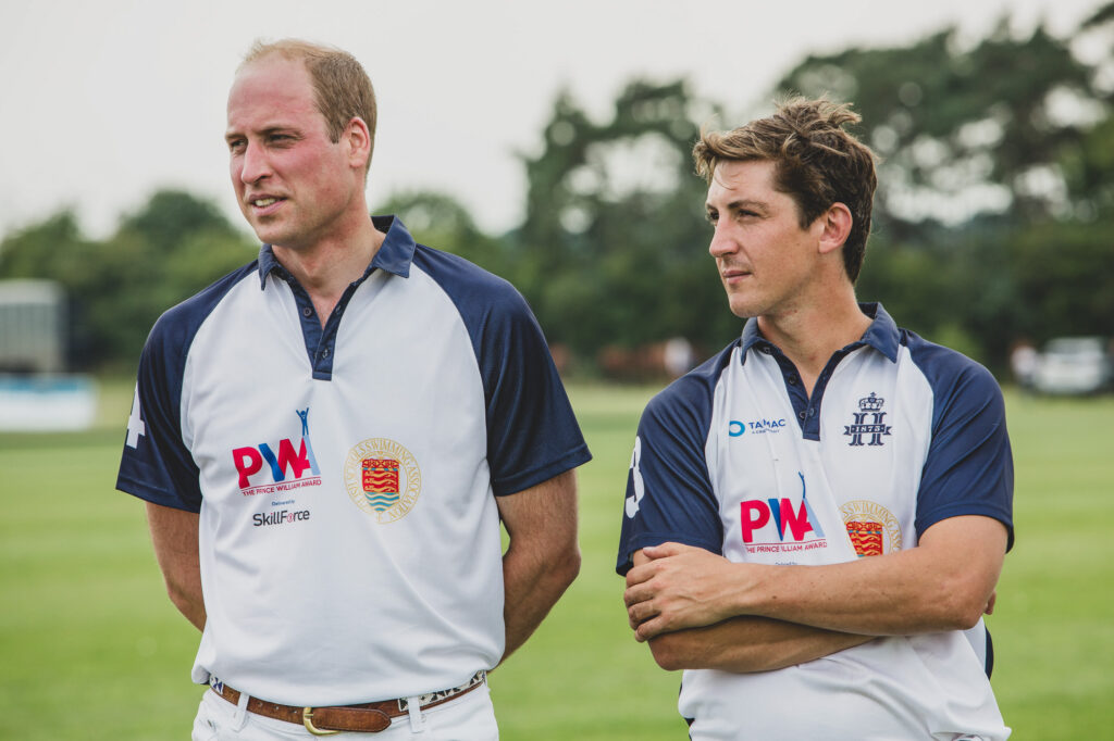 Prince William stands on a polo field with his arms behind his back after competing in a charity polo match at a Polo Club in Norfolk - Freelance Press Photography services