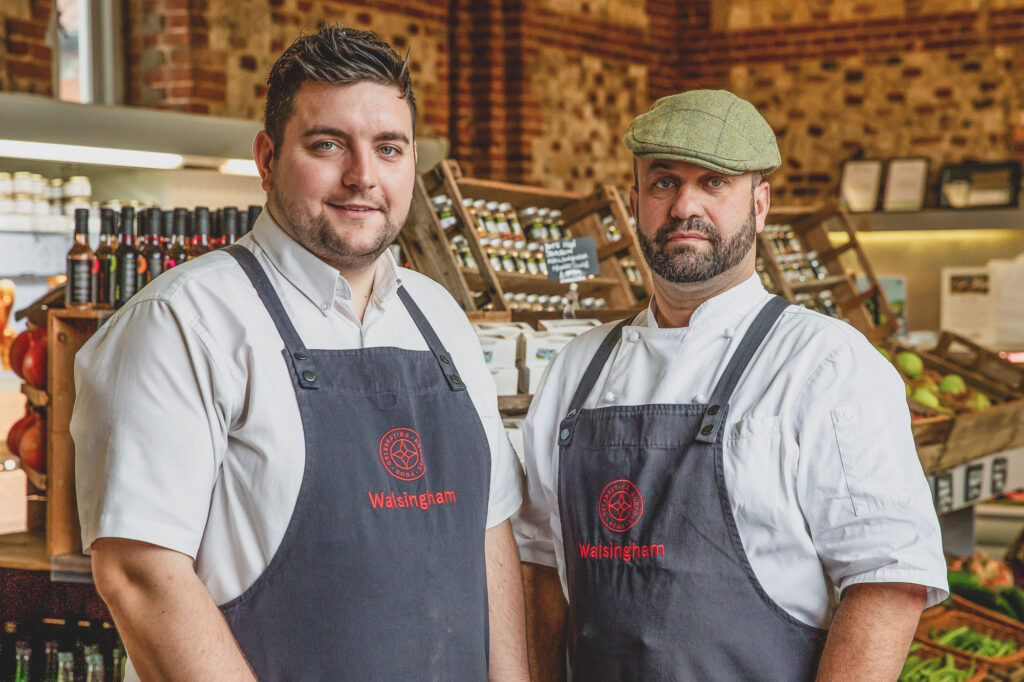 Commercial Headshot Photography of Charlie Hodson and Sam Bagge at Walsingham Farm Shop, standing together and looking to camera. Photographs by Lee Blanchflower, Blanc Creative