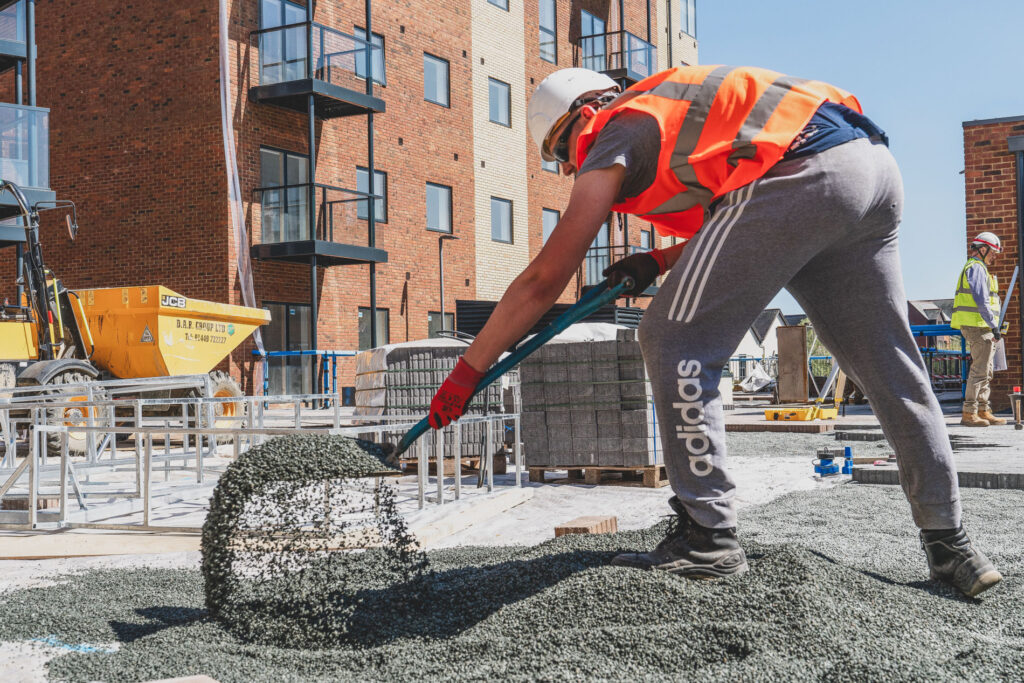 A labourer shovels rubble on a Construction Industry Photography image - Blanc Creative Norwich