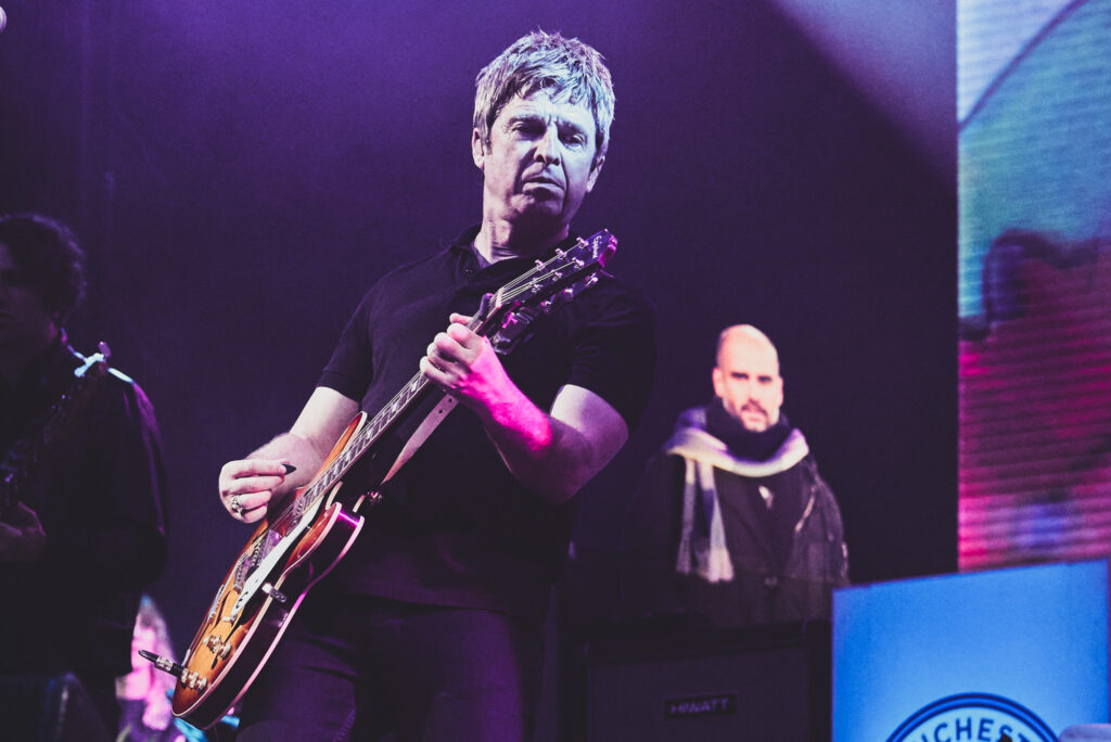 Noel Gallagher plays guitar on stage in 2023. Press Photography by Lee Blanchflower, Blanc Creative