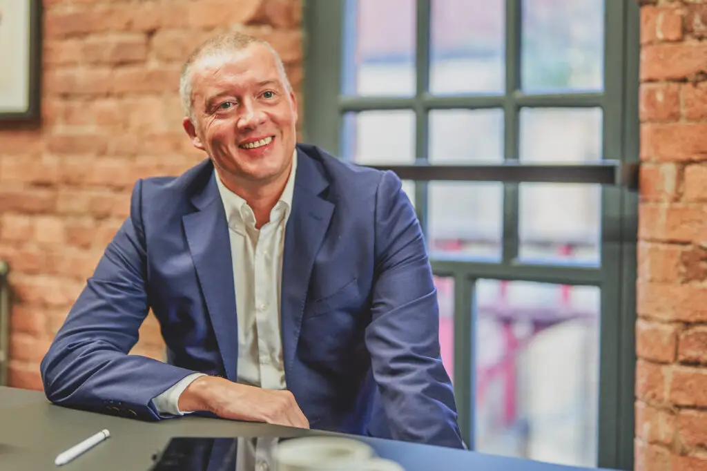 A professional male wearing formal clothing sitting in a chair in a modern office in Manchester - Blanc Creative Professional Business Portraits