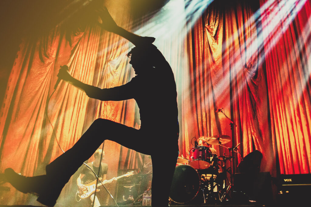 Photography Copyright : The Unseen cost. A copyrighted image of suede Front man, Brett Anderson kicking his leg in the air