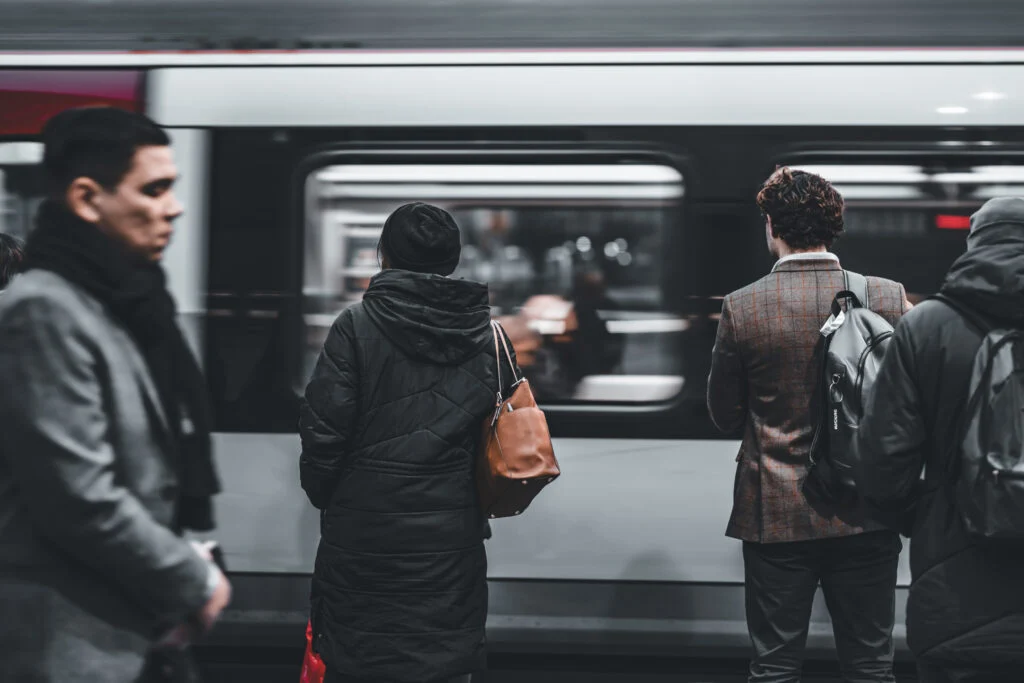 A busy London Tube Train passing Stratford Station with commuters waiting on the platform Blanc Creative Commercial Photography London
