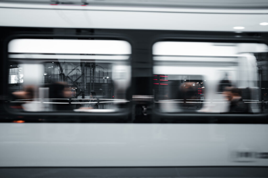 A blurred close-up of a white train carriage at night with commuters inside traveling quickly past Stratford Station - Blanc Creative Bespoke Stock Photography