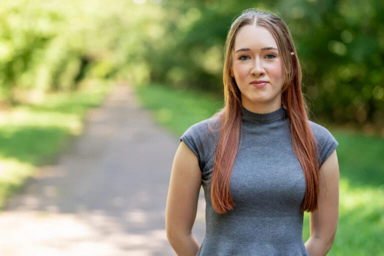 Female professional portrait, tree-lined path, natural outdoor light — environmental portrait photography Norwich by Blanc Creative