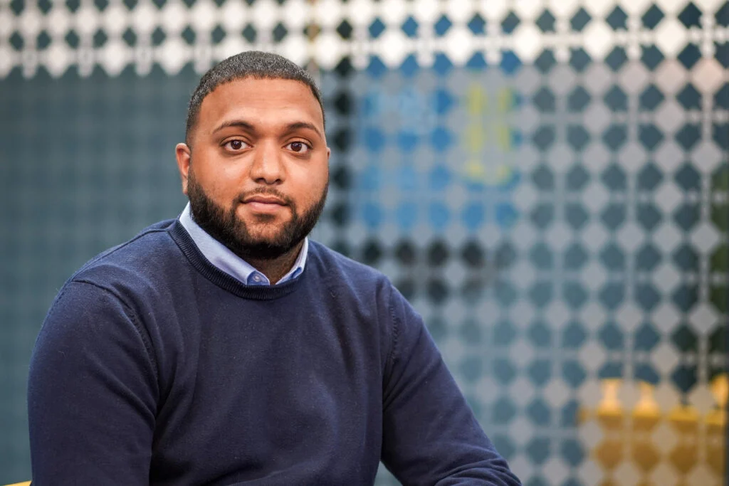 Male professional headshot, dark skin, open collar, natural office light — corporate portrait photography for professional services by Blanc Creative