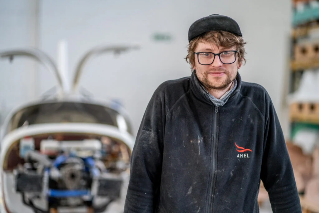 Blanc Creative Commercial Photography Norwich A young male aircraft engineer standing in the workshop with an aircraft behind him - Recruitment Photography