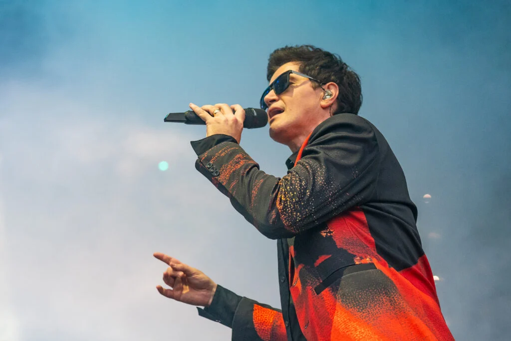 Blanc Creative Commercial Photography Norwich The Script perform on stage with Danny wearing sunglasses to cover a black eye. He is wearing a red and black Jacket against a smokey backdrop