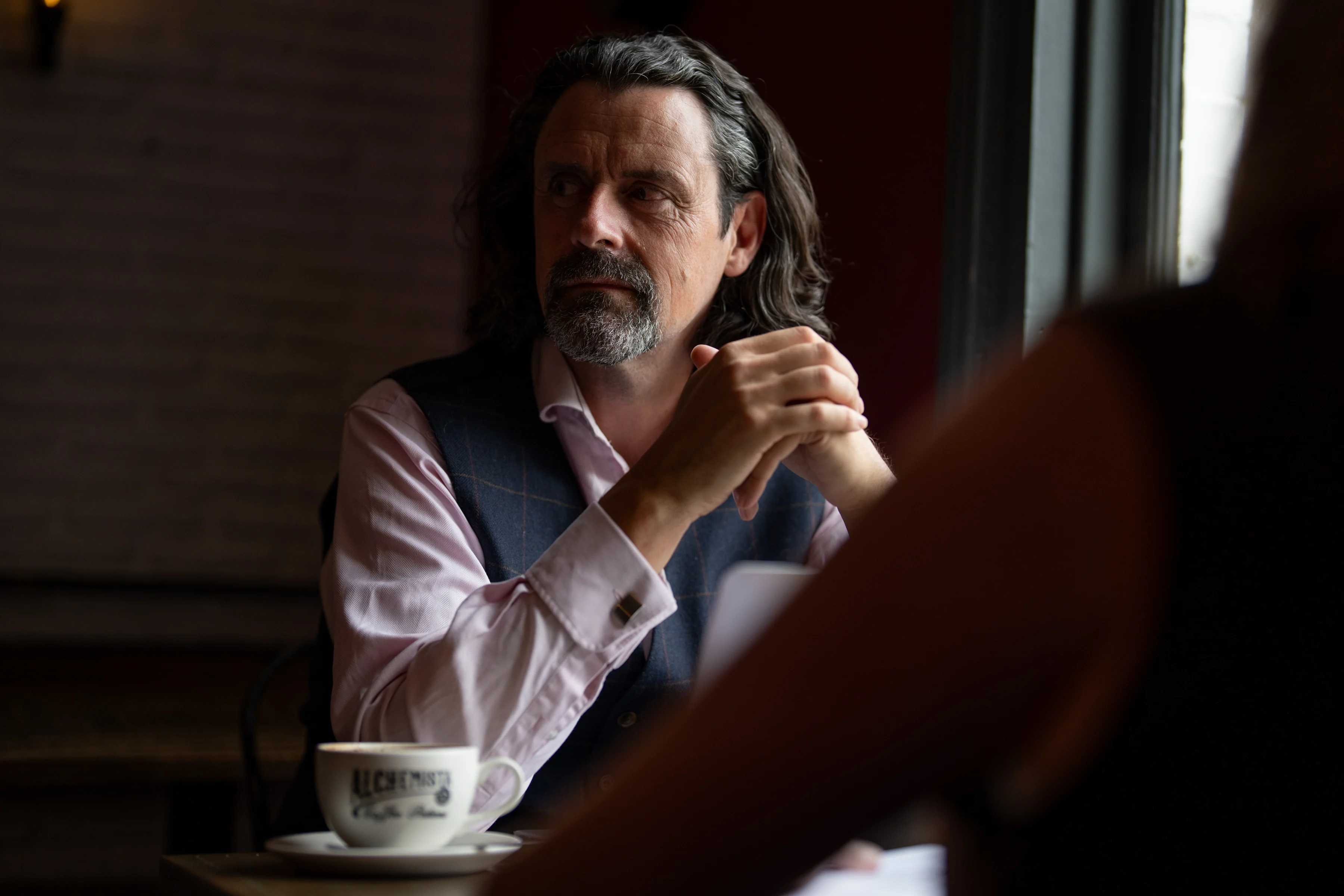 Dr Danny Kett of Rebelbridge Studio in conversation, natural light portrait in a Norwich café