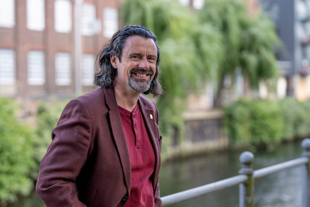 Business portrait Photography in Norwich by Blanc Creative. Danny Kett in a navy suit walking a cobbled lane