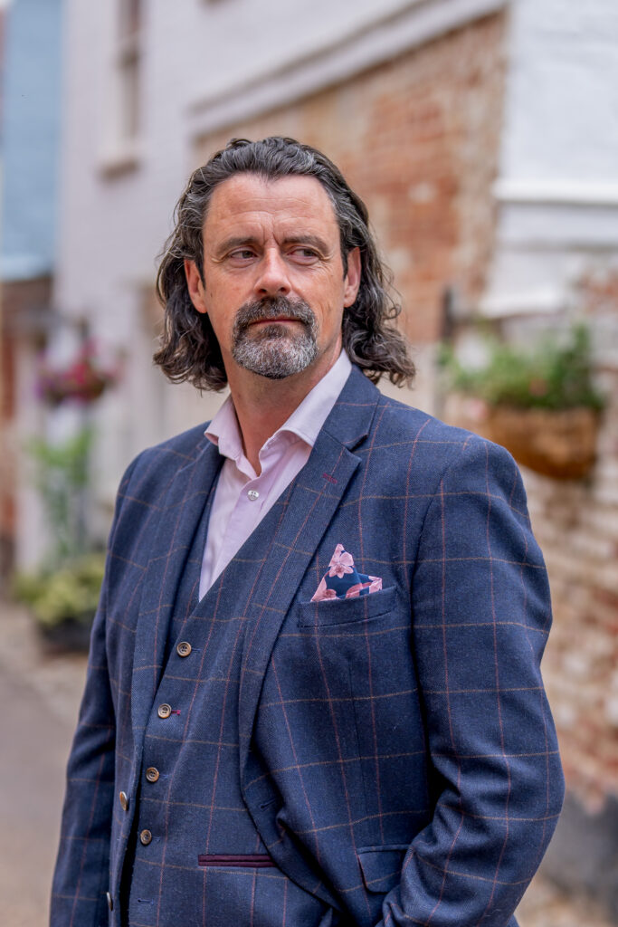 Business portrait Photography Norwich, Danny Kett in a navy suit walking a cobbled lane